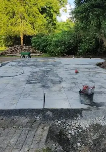 Fertiggestellte Terrasse aus Betonplatten direkt vor einem Gartenpool.