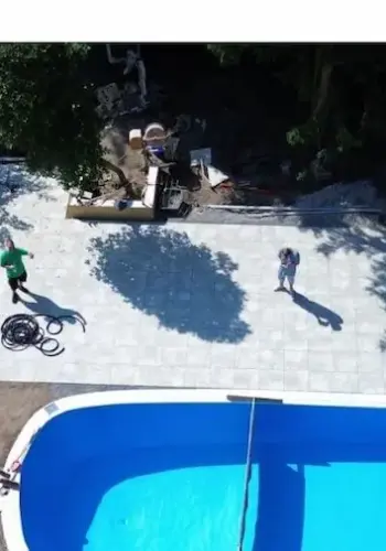 Luftaufnahme in Vogelperspektive: Neu verlegte Betonplatten-Terrasse am Pool.